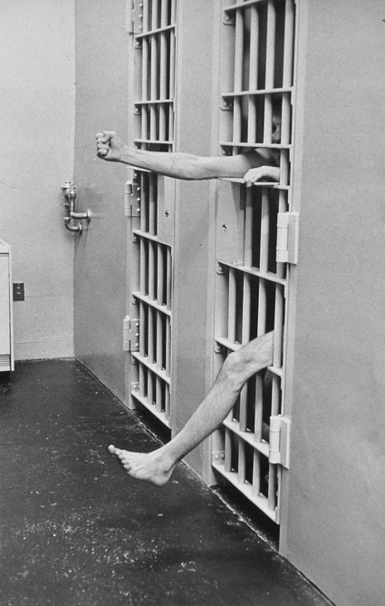 איש בכלא מוציא יד ורגל מבעד לסורגים